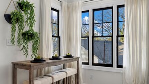 A room with a wooden table, two cushioned benches, and hanging green plants. - Luxury Modern Stay 3BR/2BA Pet Friendly Home Near UAB (Birmingham)