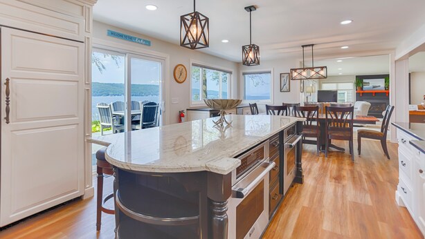 A kitchen with a large island, wooden flooring, and a view of the lake.