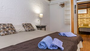 Une chambre d’hôtel avec un lit, des oreillers, une table de chevet, une lampe et un plancher en bois.