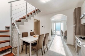 A modern kitchen with a dining area, a staircase, and a view to the outside. - Nesso Mosaic - MyHomeinComo (Nesso)