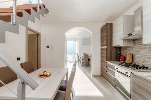 Une cuisine moderne avec un coin repas, un escalier et une vue sur l’extérieur.