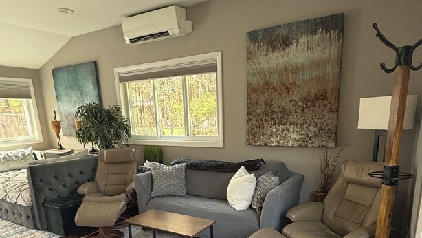 Een woonkamer met een grijze bank, twee fauteuils, een salontafel en een groot schilderij aan de muur.