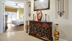 A hotel lobby with a wooden reception desk, a large mirror, and a vase. - Elegant Escape at Reunion – Near Disney w/ Pool (Kissimmee)