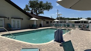 Ein Poolbereich mit Liegestühlen, Sonnenschirmen und einem klaren, blauen Pool.