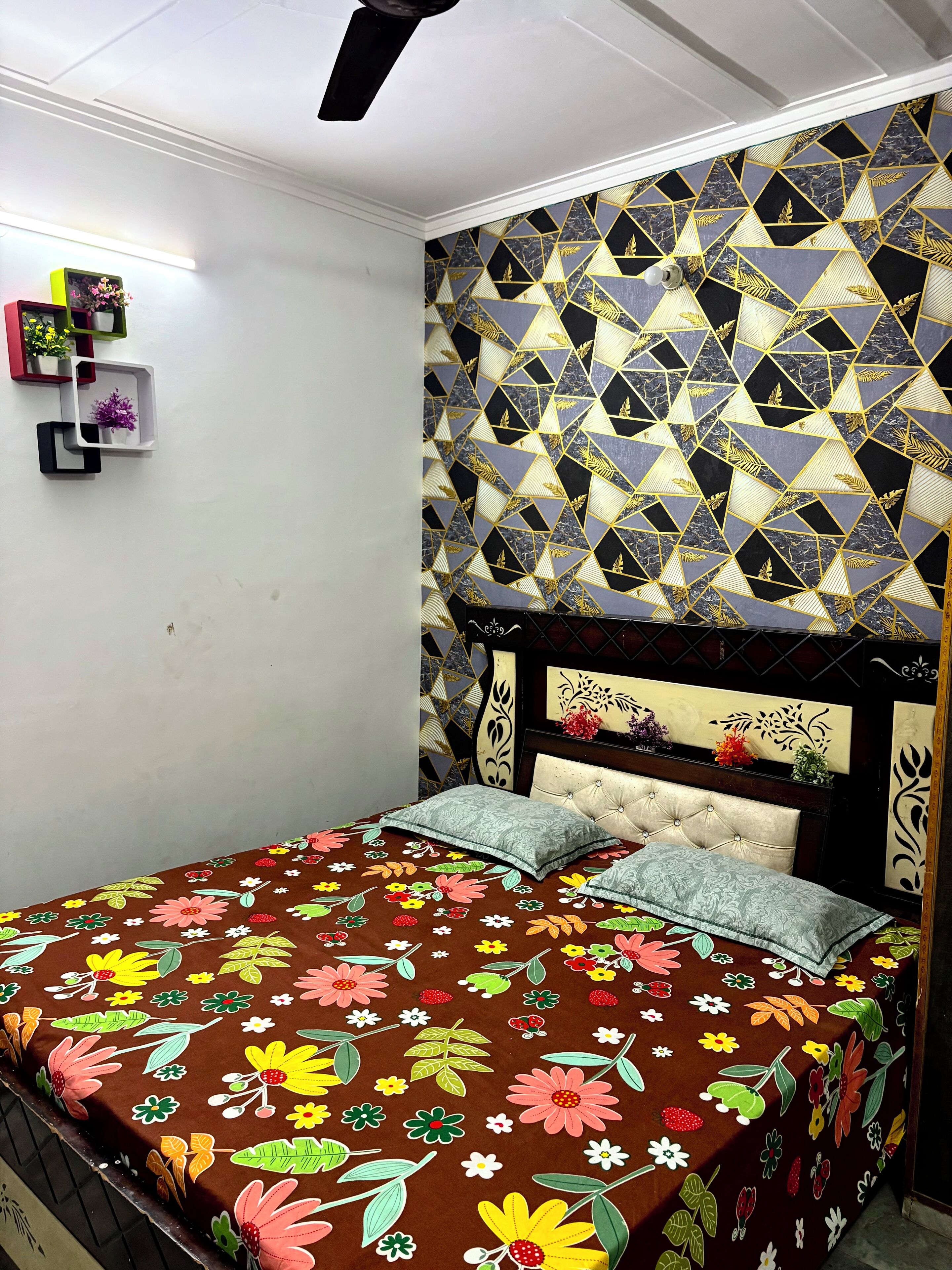 Une chambre à coucher avec un lit, une tête de lit décorative et des étagères murales ornées de fleurs.