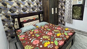 Ein Schlafzimmer mit einem Bett, einem Kleiderschrank, einem Deckenventilator und Wandverkleidung mit Muster.