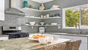Cozinha moderna com backsplash de azulejos cinzas, eletrodomésticos de aço inoxidável e um espaço para refeições rápidas no balcão.