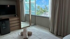Camera d'albergo con un letto, una TV, una scrivania e una finestra con tende.