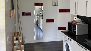 A modern kitchen with a washing machine, a wooden ladder, and a mirror reflecting the kitchen. - Zenith/Stadium/Expo Park/Sports Palace, Apt 2 rooms 4pers private parking (Caen)