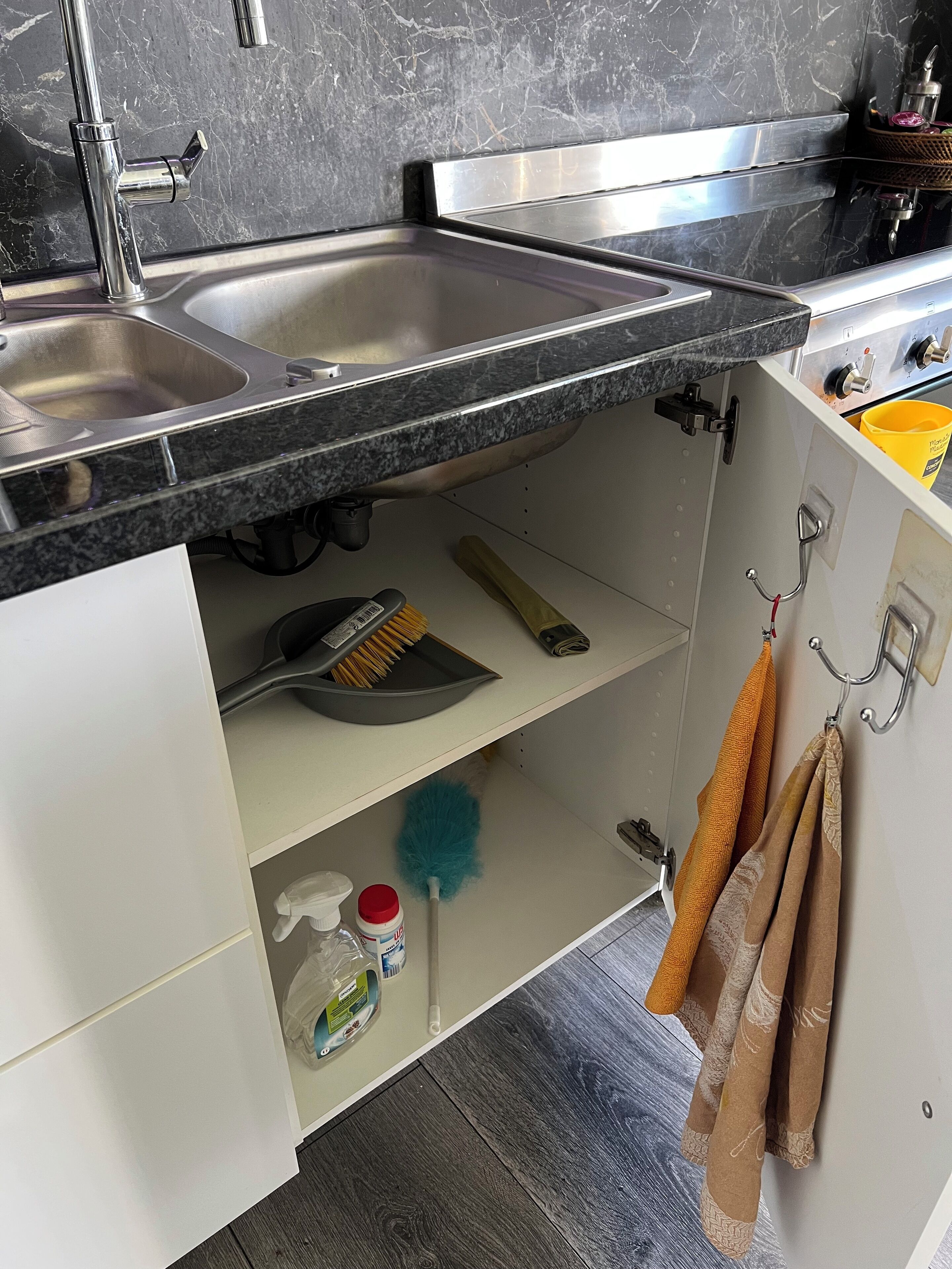 Ett kök med två diskhoar i rostfritt stål, en sopborste, en dammsvabb och en gul hink.