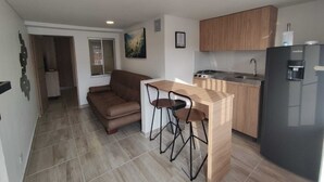 Una cocina compacta con cubierta de madera, estufa a gas y refrigerador negro.