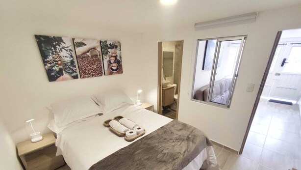 Un dormitorio ordenado con cama, mesitas de noche, un espejo y una ventana.