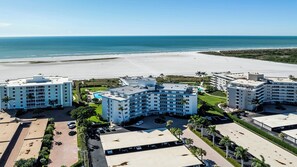 A beachfront hotel with multiple buildings, a swimming pool, and a beach in the background.