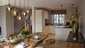 A dining area with a wooden table, chairs, and hanging pendant lights. - Haus Goed Libben - Moin and welcome to Haus Goed Libben - to (Sylt)