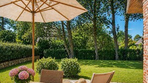 A patio with a table, chairs, a wicker chair, a straw hat, and a large umbrella. - Haus Goed Libben - Moin and welcome to Haus Goed Libben - to (Sylt)