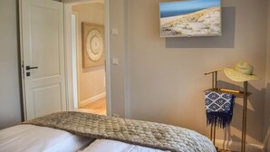 A bedroom with a bed, a door, a wall-mounted TV, and a framed picture. - Haus Goed Libben - Moin and welcome to Haus Goed Libben - to (Sylt)