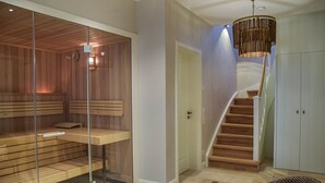 A modern interior with a sauna, a staircase, and a wicker chair. - Haus Goed Libben - Moin and welcome to Haus Goed Libben - to (Sylt)