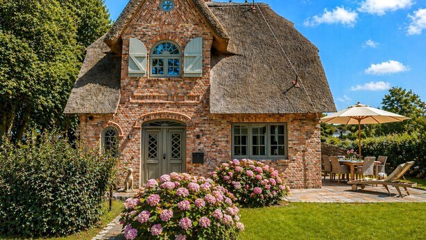 A brick house with a thatched roof, a central door, and a small porch area. - Haus Goed Libben - Moin and welcome to Haus Goed Libben - to (Sylt)