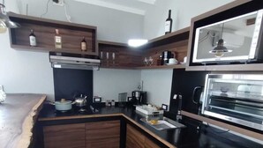 Una cocina moderna con armarios de madera, encimera negra, horno empotrado y microondas.