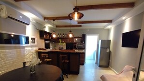 Una cocina moderna con una isla central, taburetes de madera y una mesa de comedor con un florero.
