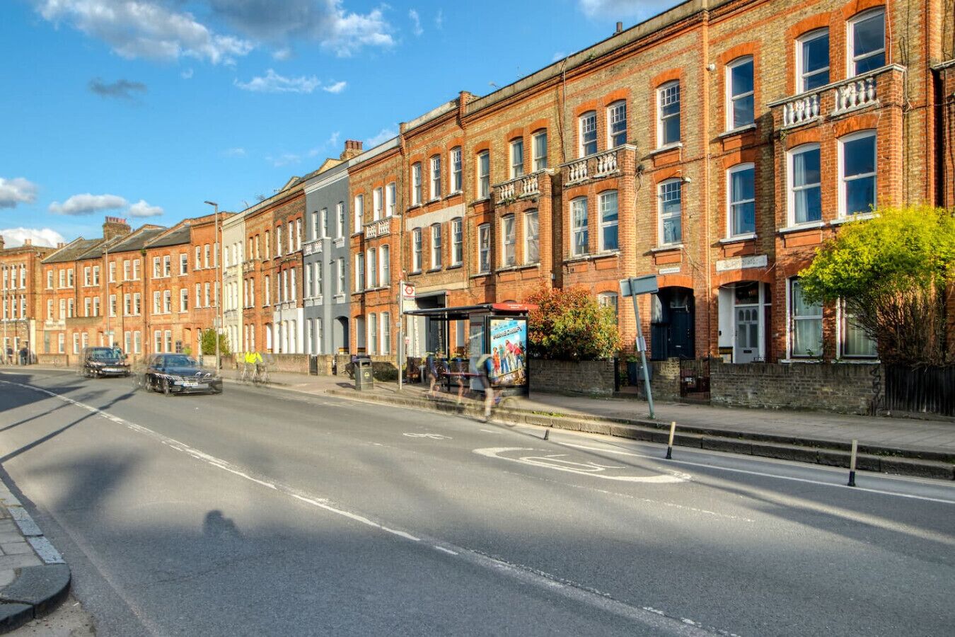 A row of red brick townhouses with a clear road in front.