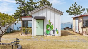 A small, single-story building with a green door, a cactus mural, and a bench in the foreground. - Mu-an Prejong Dokchae Pension (Muan)