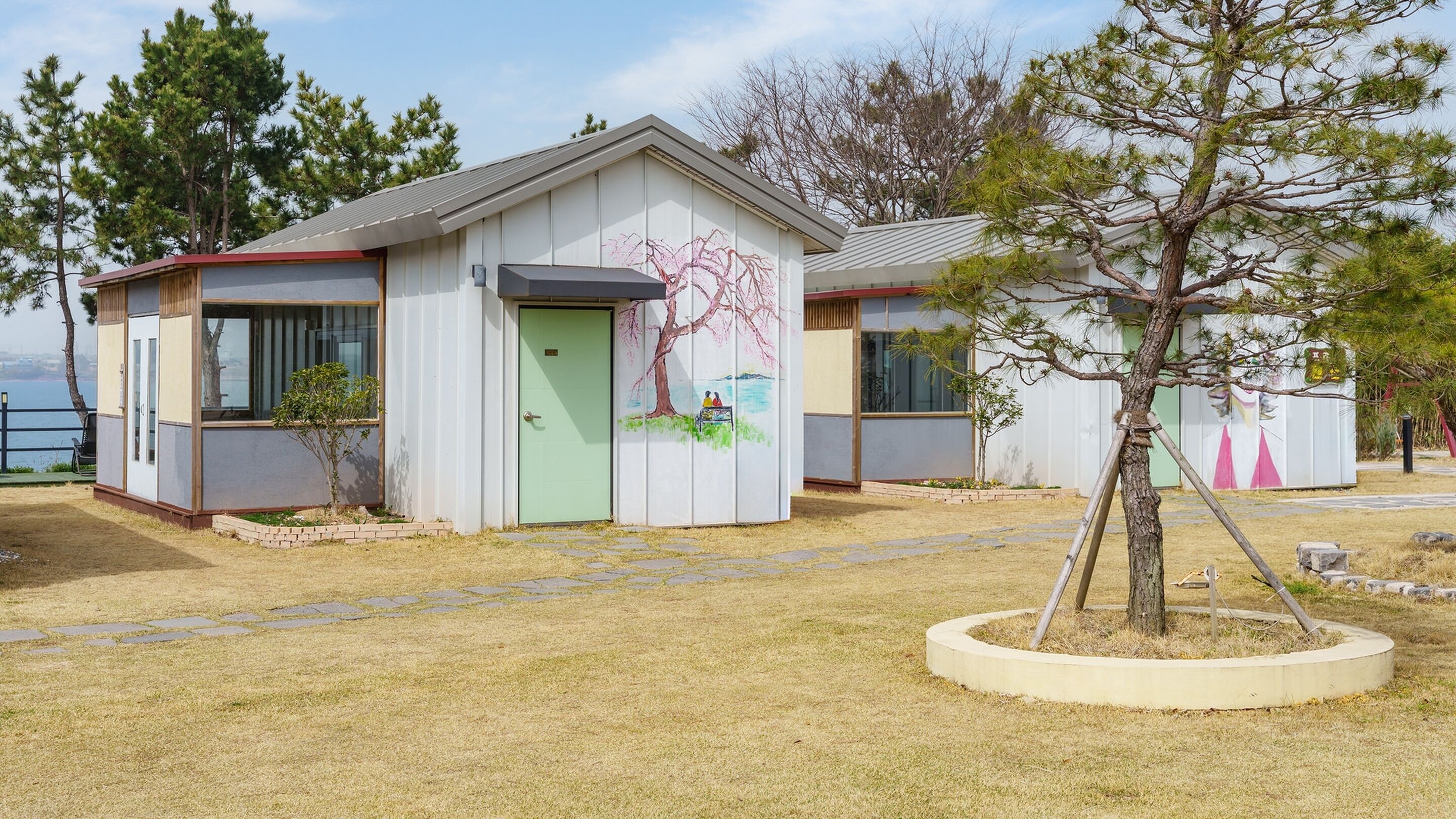A small building with a green door and a mural of a tree and people on the side.