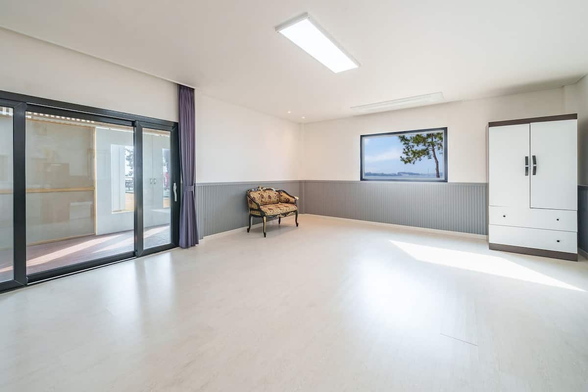 A spacious room with a sliding glass door, a sofa, a wardrobe, and a framed picture on the wall.