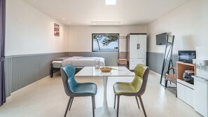 A compact hotel room with a bed, a small table with chairs, a television, and a kitchenette. - Mu-an Prejong Dokchae Pension (Muan)