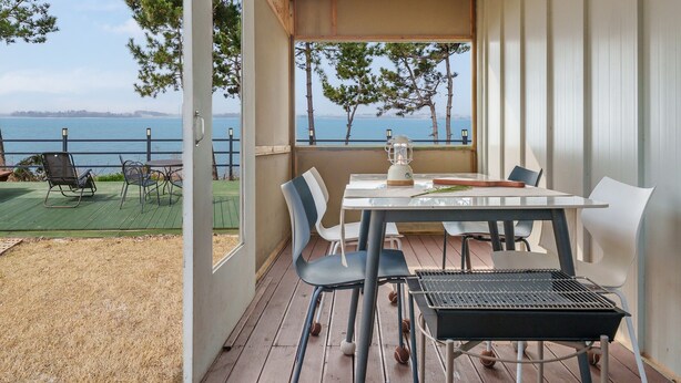 A balcony with a table and chairs, overlooking a body of water and trees. - Mu-an Prejong Dokchae Pension (Muan)