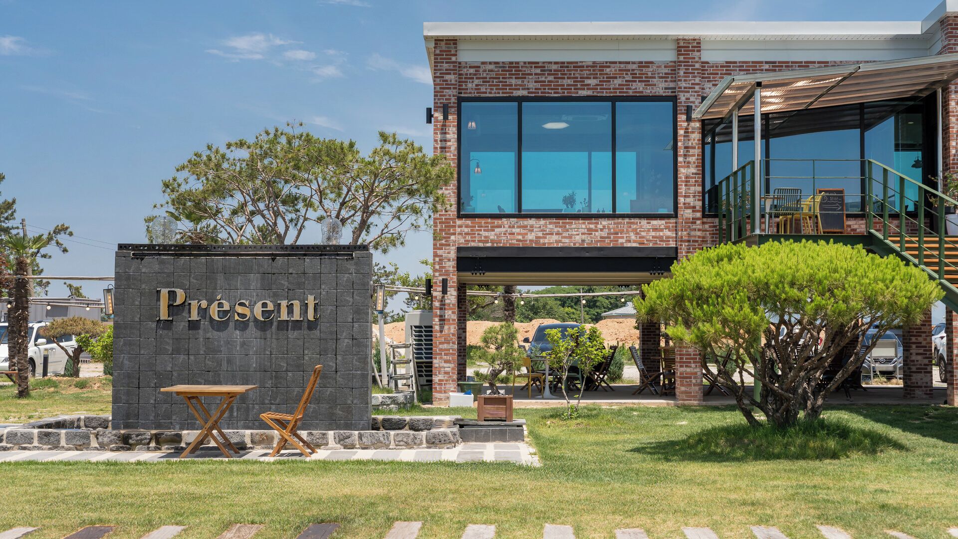 Un edificio moderno con fachada de ladrillo, ventanas grandes y un letrero que dice 'Present'.