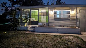 Una casa de un piso con una puerta verde, un pequeño porche y el número 131 en el lateral.