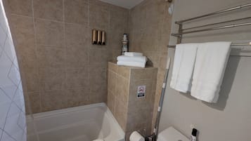 Een badkamer met een bad, toilet en douche.