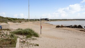 En sandstrand med ett räddningstorn, en metallstege och en byggnad i bakgrunden.