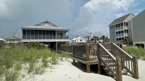 A beachfront property with a wooden deck and a two-story building.