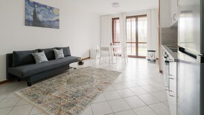 A modern living room with a sofa, a dining area, and a kitchen.