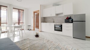 A modern kitchen with white cabinets, a stainless steel refrigerator, and a built-in oven.