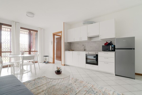 A modern kitchen with white cabinets, a stainless steel refrigerator, and a built-in oven.