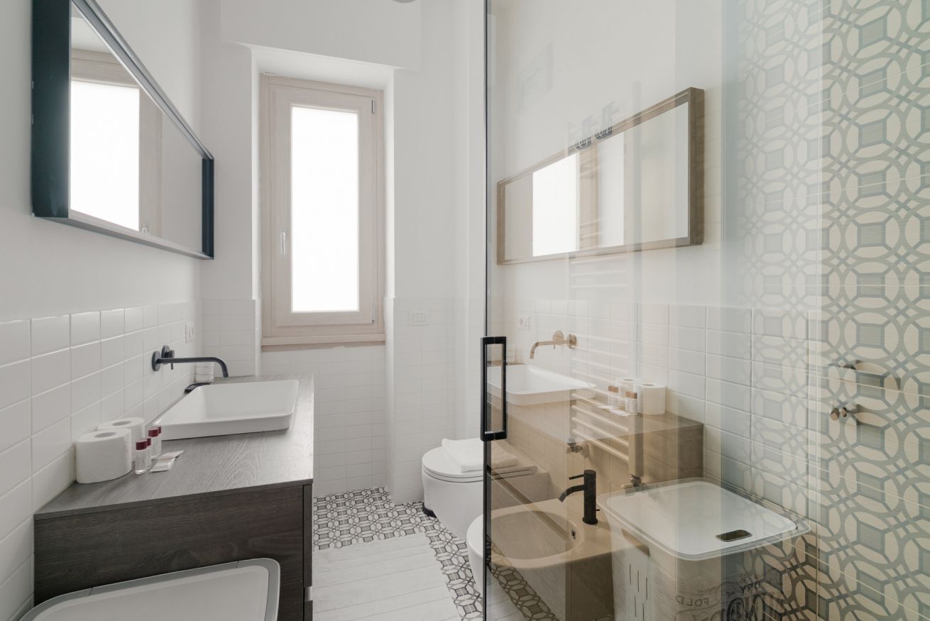 Een moderne badkamer met een douchecabine van glas, een witte wastafel en een toilet.