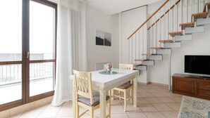Uma sala de estar moderna com uma mesa de jantar, cadeiras, uma TV e uma escada.