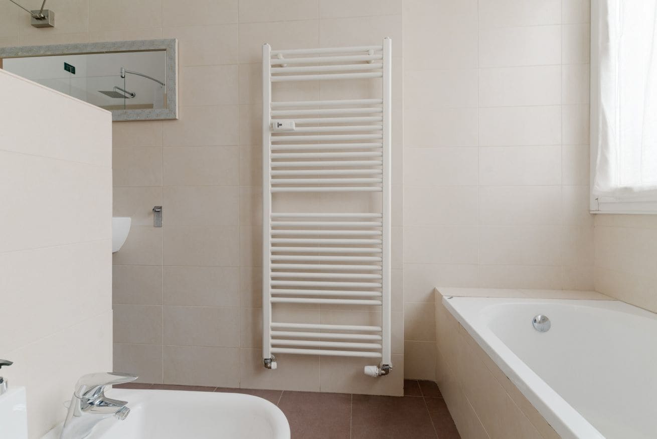 Une salle de bain avec une baignoire blanche, un porte-serviettes blanc et un miroir au mur.