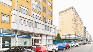 A row of parked cars along a street with multi-story yellow buildings featuring storefronts with signage for Lloyd Adriatico and Allianz. - GuestHost - Cozy 78 sqm apartment, able to accommodate up to 4 people, located on the first floor of a building with lift.The property is located 650m from the Famagosta stop of the green metro line M2, which allows you to reach Piazza Duomo, Central Sta (Milano)