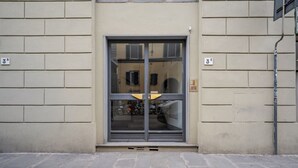 Ein Gebäudeeingang mit Glastür, Backsteinwand und Metallpfosten.