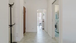 A hallway with a coat rack, a door, and a laundry area with a washing machine.