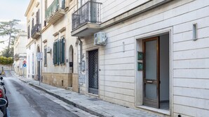 A street view with a building featuring a large window, a door, and a small balcony.