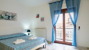 A bedroom with a bed, a radiator, a window with curtains, and artwork on the wall.