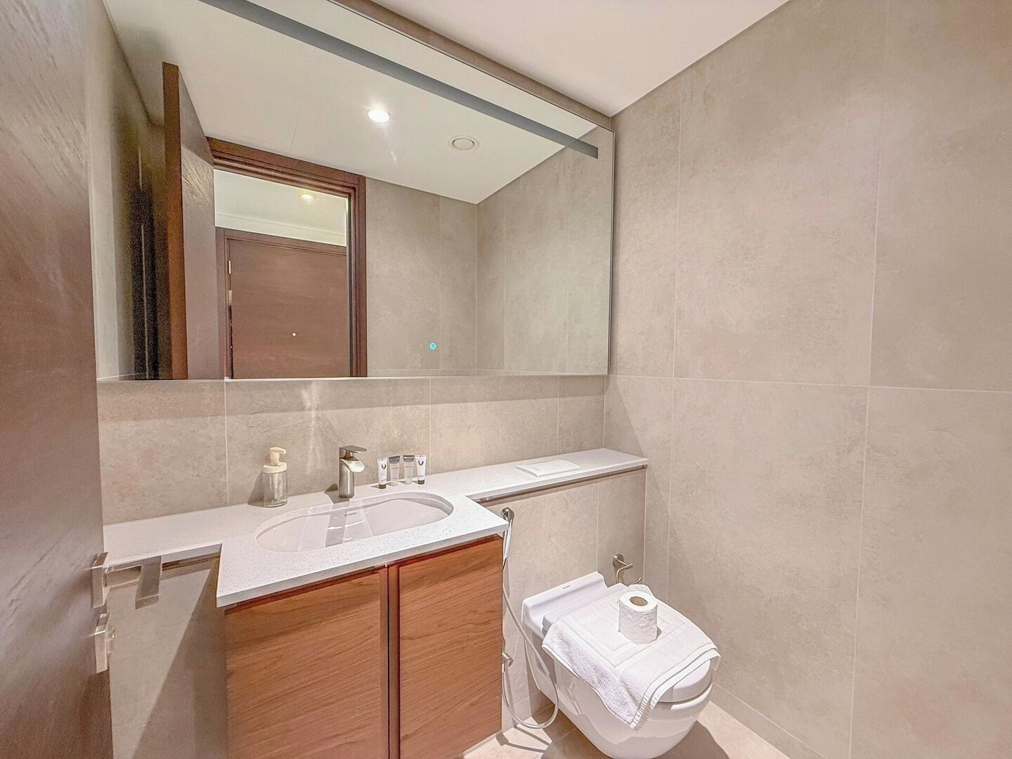 Une salle de bain moderne avec un grand miroir, un lavabo équipé de produits de toilette et des toilettes.