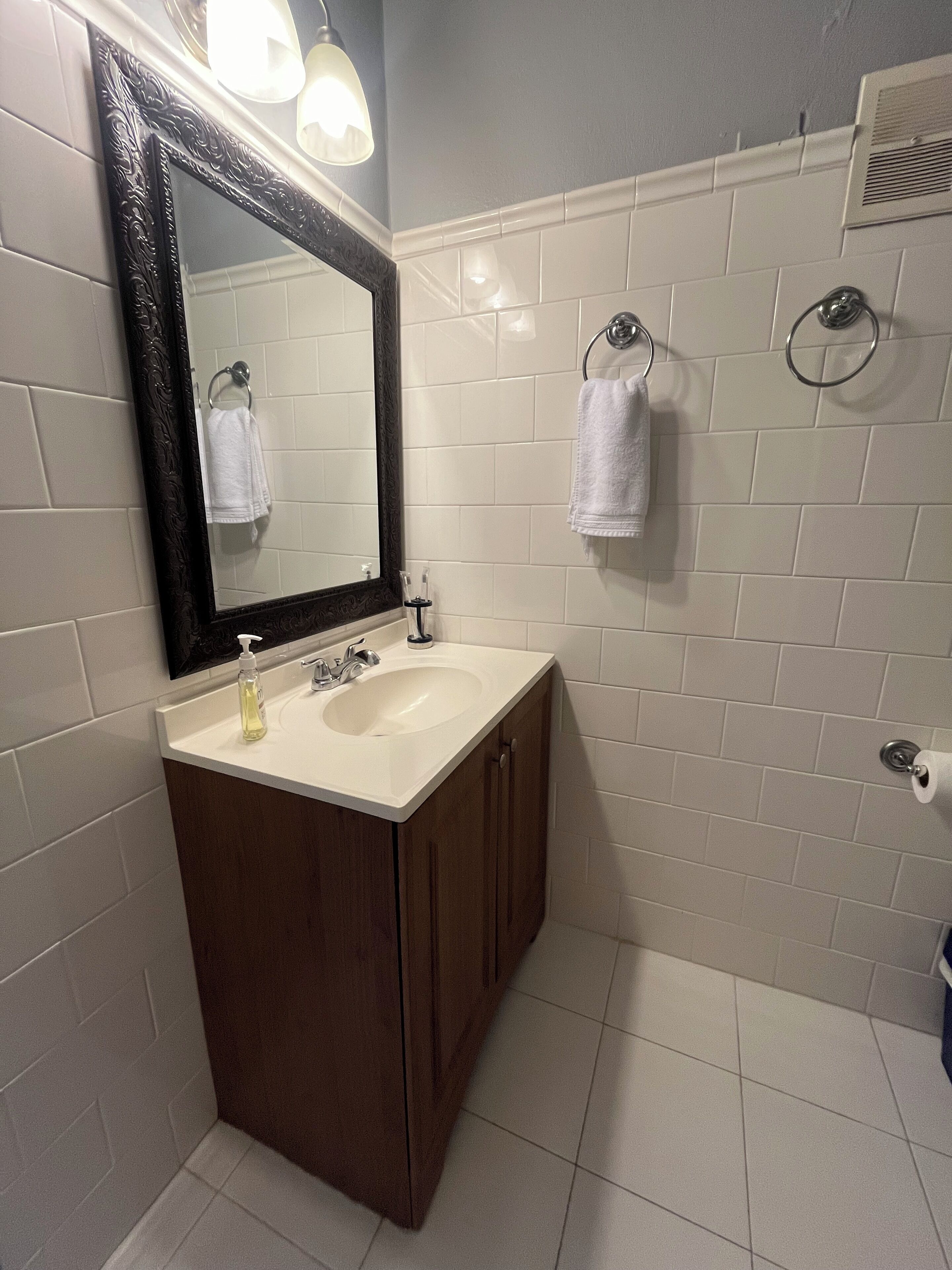 Une salle de bain avec un lavabo blanc, un meuble-lavabo en bois foncé et un grand miroir.