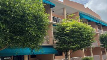 A multi-story building with balconies, a parking area with yellow lines, and a clear sky.