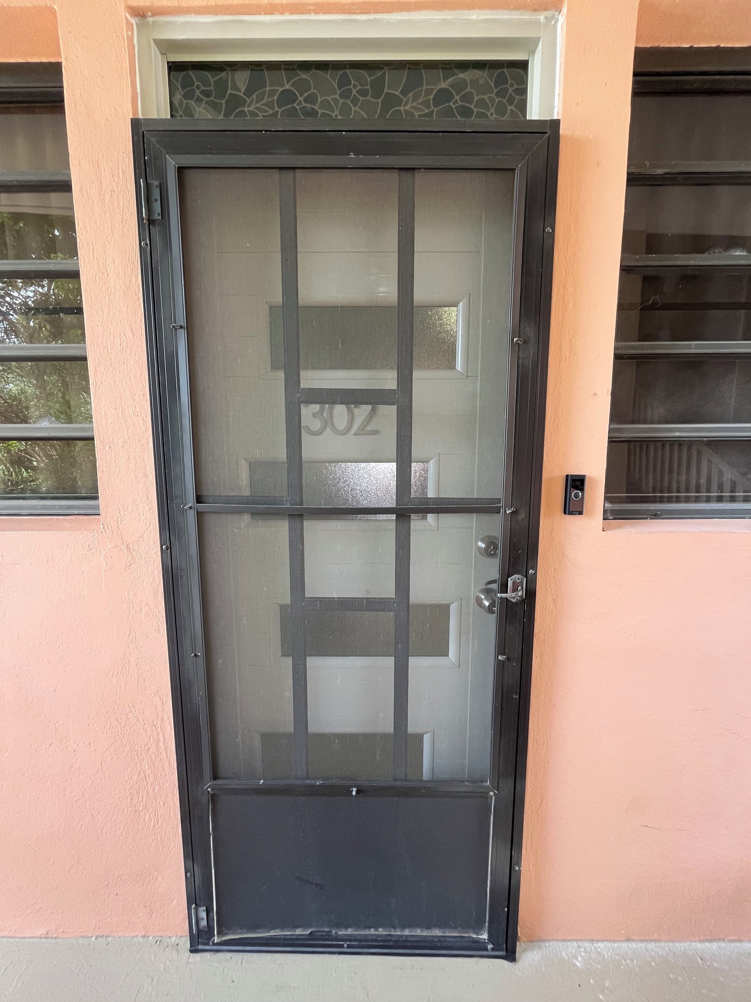 A door with a number "302" on it, a keypad lock, and a small window above the door.